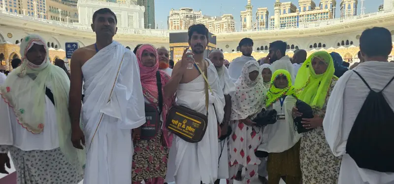 Madni Tour & Travels pilgrims in Ihram at Masjid al-Haram with the Kaaba behind, Makkah