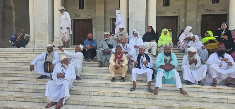 Pilgrims from the group resting and making dua on the marble steps of a mosque