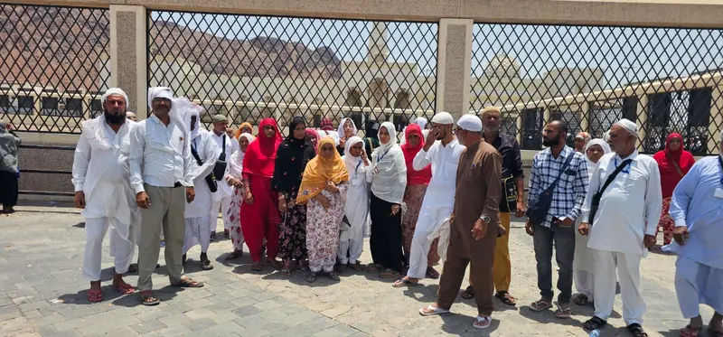 Men and women from the Madni Tour & Travels group standing together during a Ziyarat visit